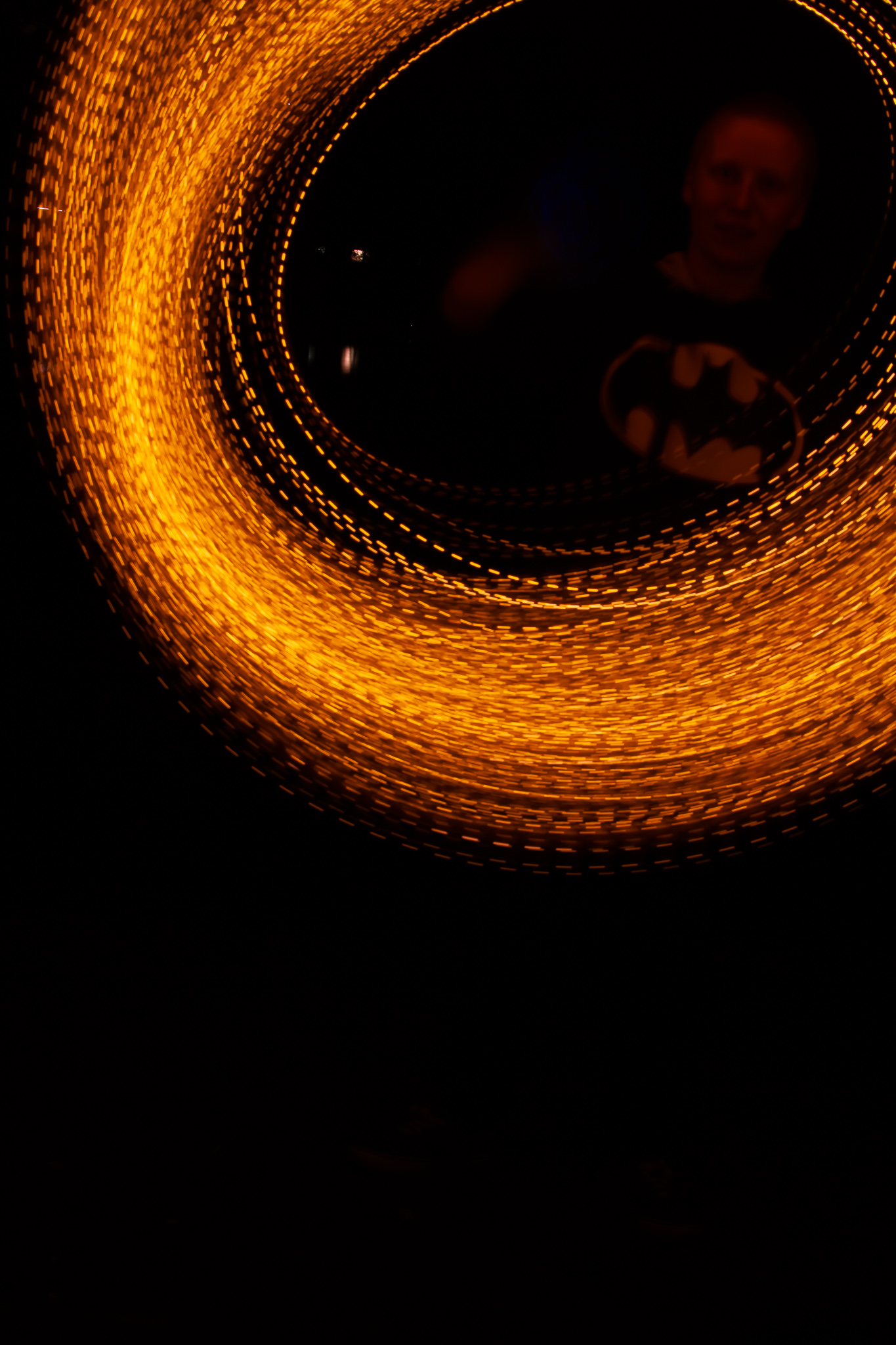the subject in the batman hoodie once again surrounded by orange light trails, only this time the trails are dotted and not sparks